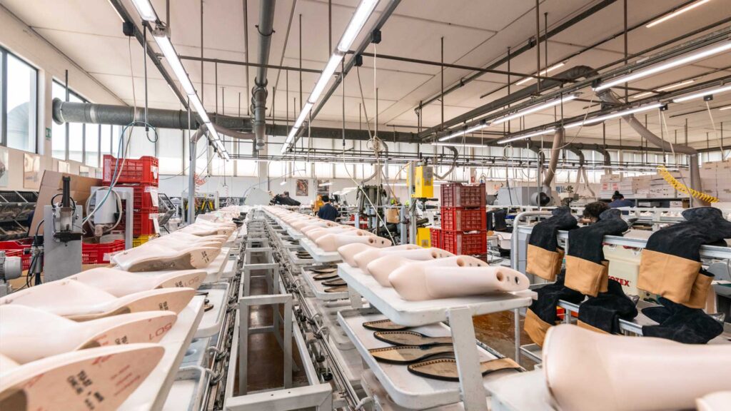 Laboratorio Cavallini con postazioni di lavoro e forme per scarpe in legno, artigiani al lavoro nella produzione artigianale
